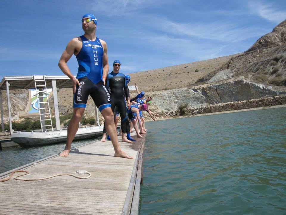 Athletes preparing for an open-water swim from a wooden jetty
