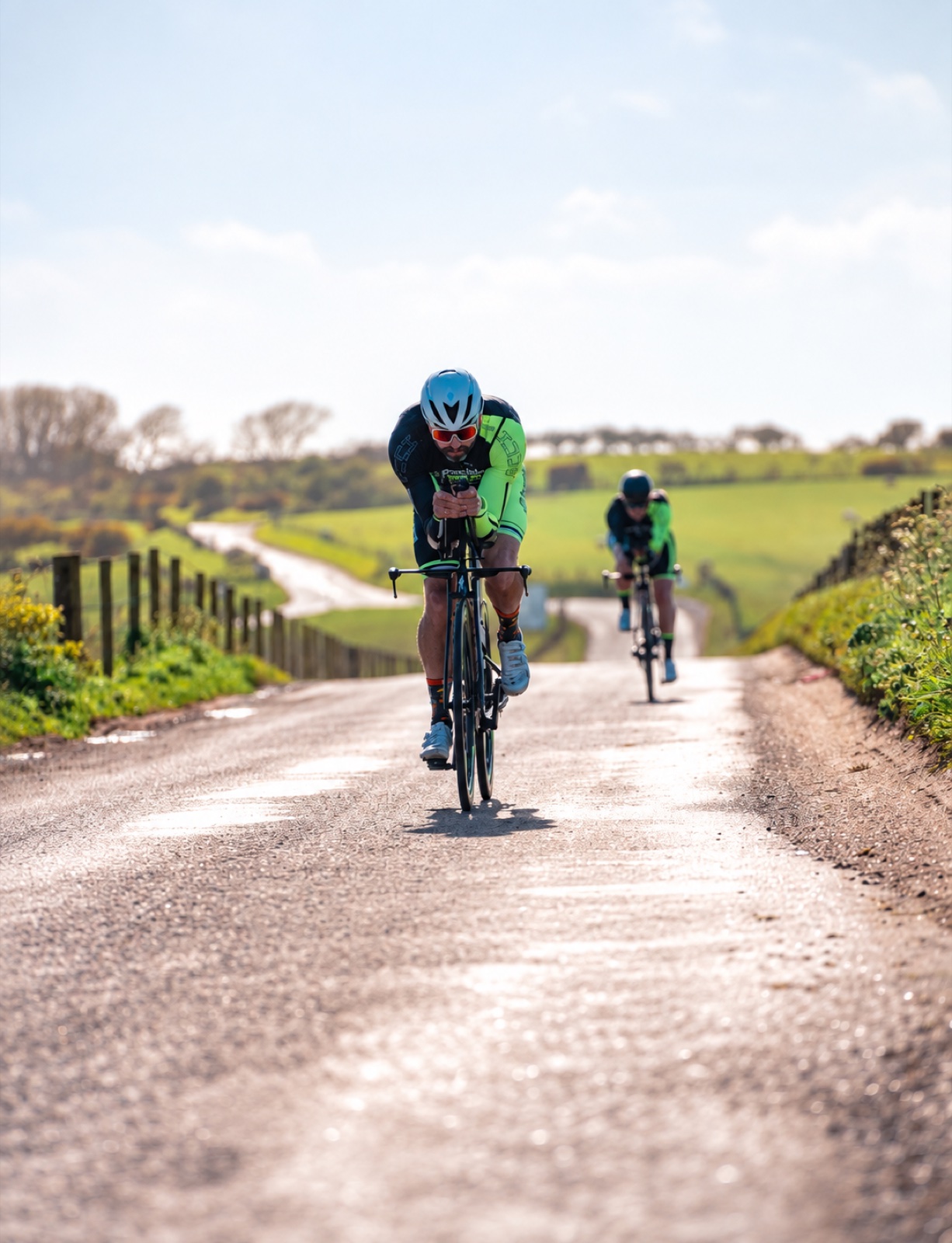 Two Precision athletes cycling on a country road