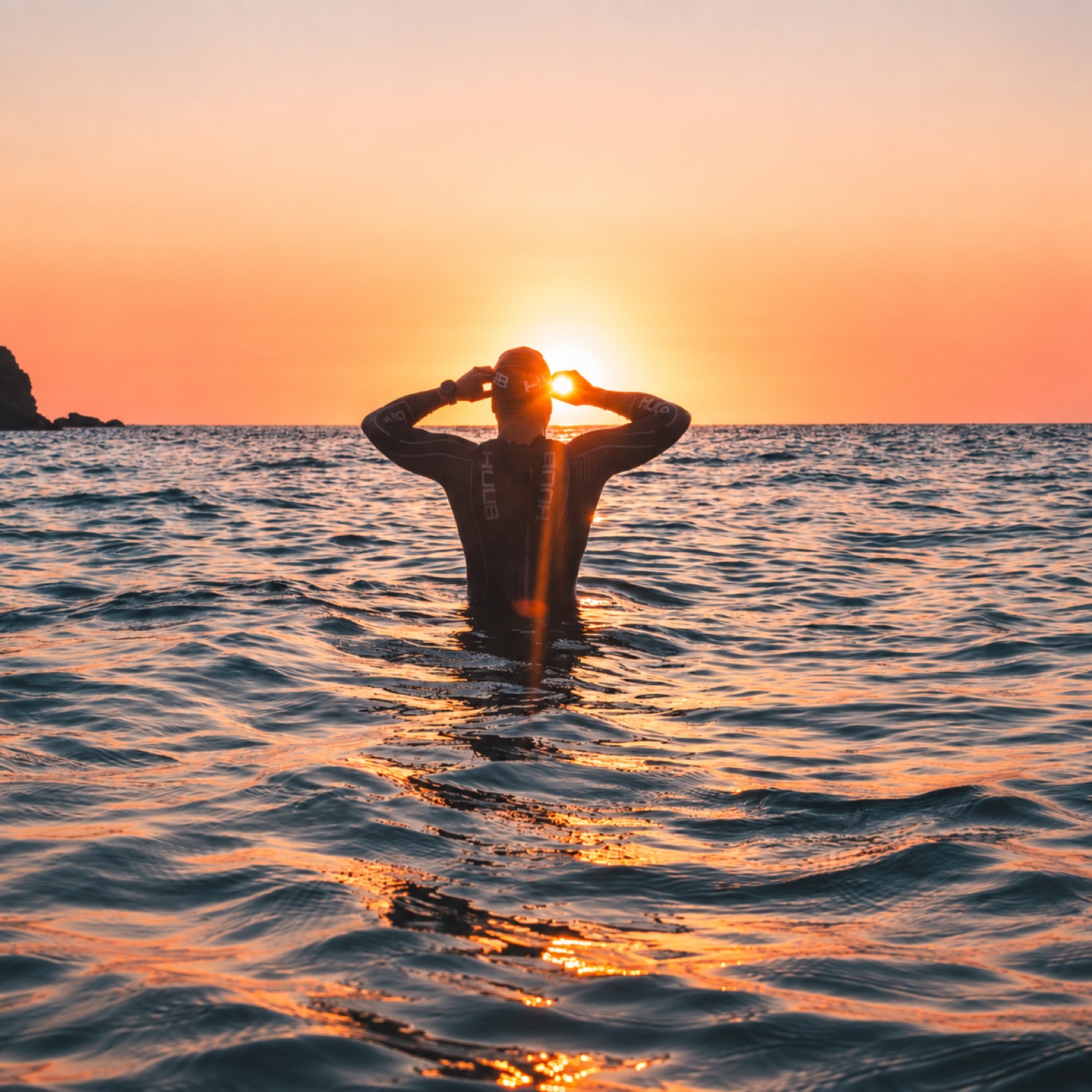 Swimmer adjusting goggles in the sea at sunset
